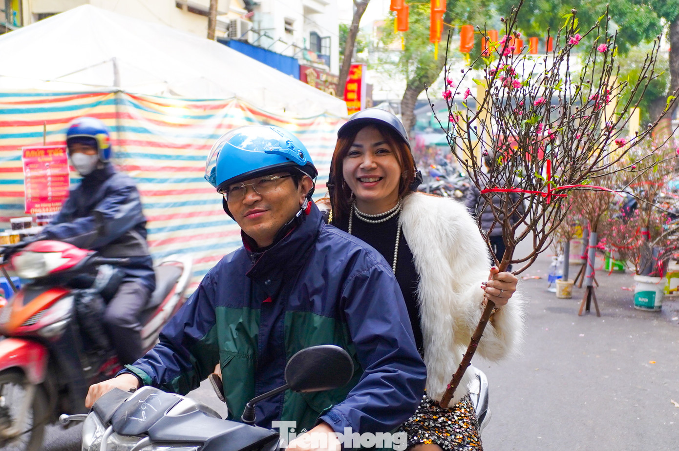 Vợ chồng anh Hưng (quận Long Biên) phấn khởi vì mua được cành đào đẹp. Anh Hưng cho biết: "Hôm nay tranh thủ cuối tuần, tôi và vợ được nghỉ làm nên xuống phố sắm ít đồ Tết cho nhà. Không khí năm mới đã rất nhộn nhịp trên các khu chợ".