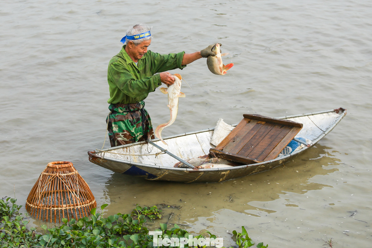 Trong một cú chụp nơm, ông Nguyễn Văn Đào bắt được hai con cá và tự hào giơ lên khoe với mọi người trong làng.