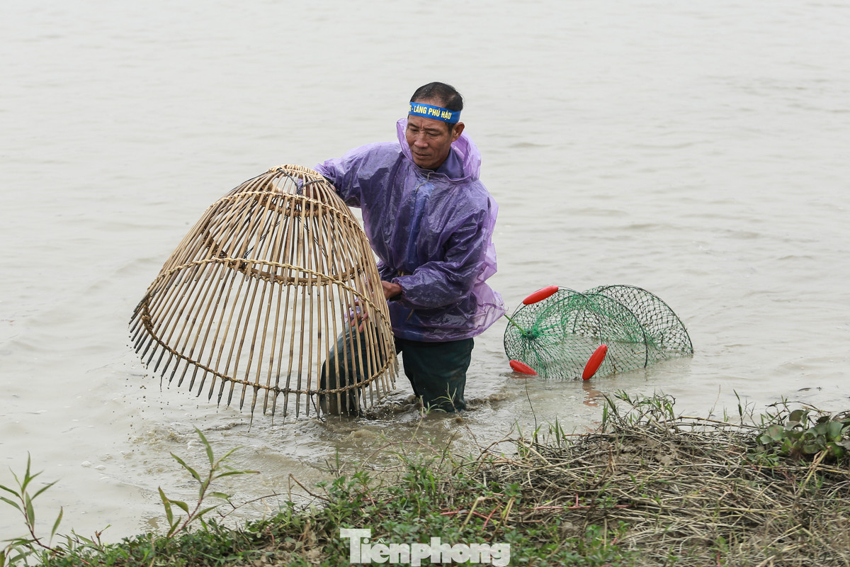 Nhiệt độ ngoài trời lúc 7 giờ sáng nay tại Vĩnh Phúc khoảng 16 độ. Nhiều người tham gia hội bắt cá phải mặc áo mưa để chống rét.