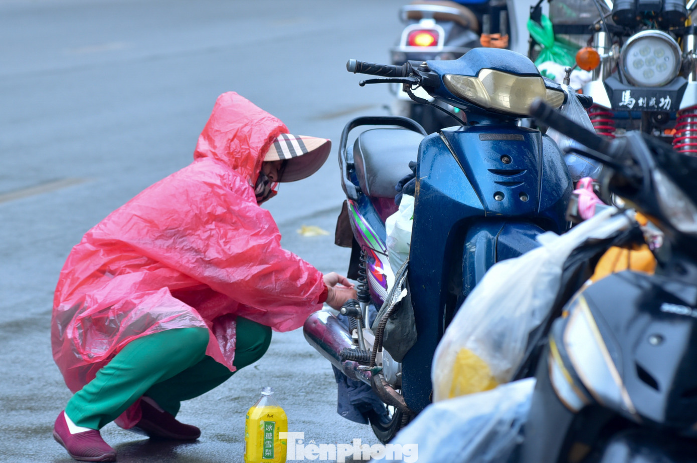 Một người phụ nữ loay hoay sửa xe ngay trên đường.