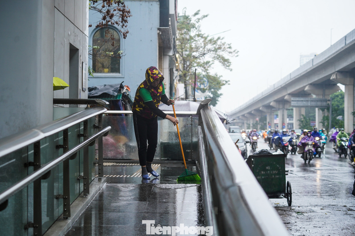 Trời mưa, người dân qua lại đông đúc, nhân viên vệ sinh của ga tàu điện liên tục phải lau dọn để tránh trơn trượt.