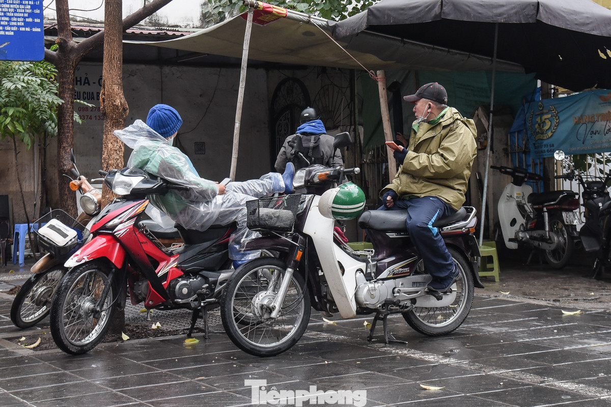 Tài xế lái xe ôm mặc áo mưa kín mít túm tụm trò chuyện chờ khách.