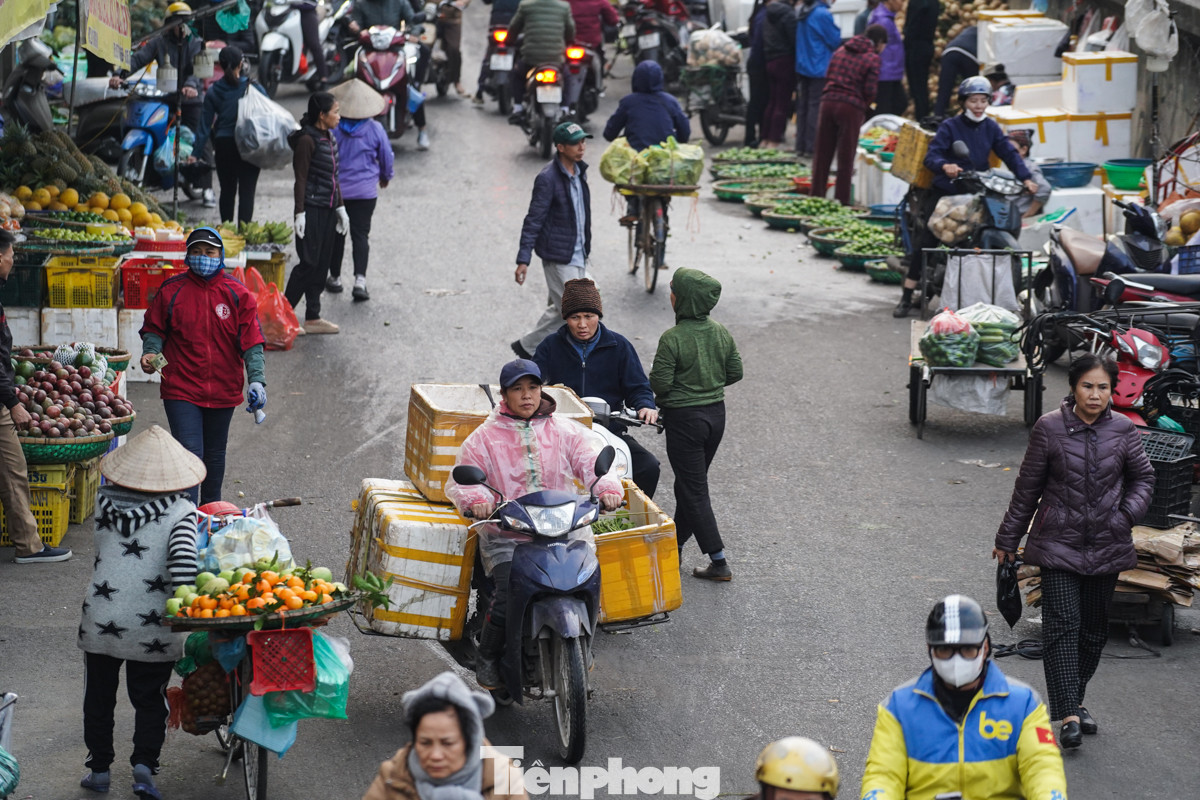 Người dân làm việc ngoài trời phải mặc áo mưa để tránh rét.