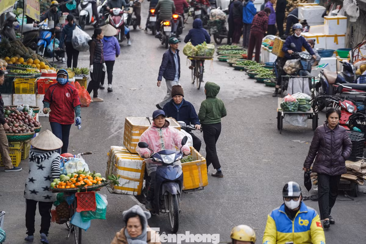 Người dân làm việc ngoài trời phải mặc áo mưa để tránh rét.