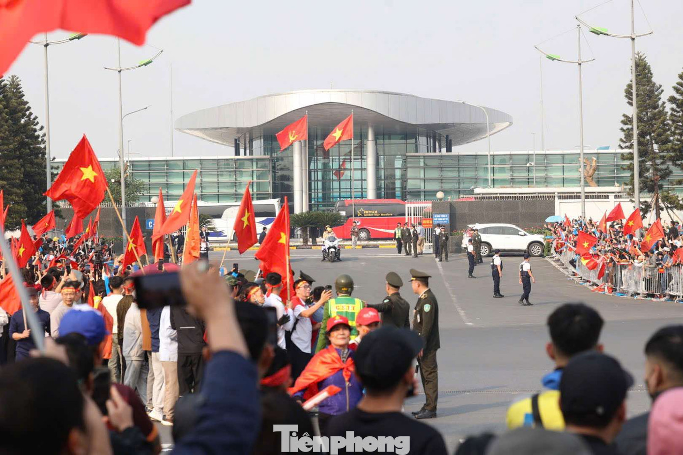 Người dân cầm cờ Tổ quốc đứng quanh sân bay Nội Bài chào mừng các 'người hùng' trở về.