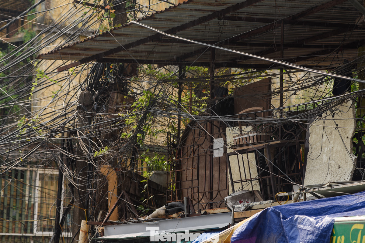 Dây điện chằng chịt sát tường, lan can khu tập thể cũ tại ngõ A8 Tôn Thất Tùng. Thậm chí có người còn bất chấp nguy hiểm bán hàng ngay dưới cột điện.