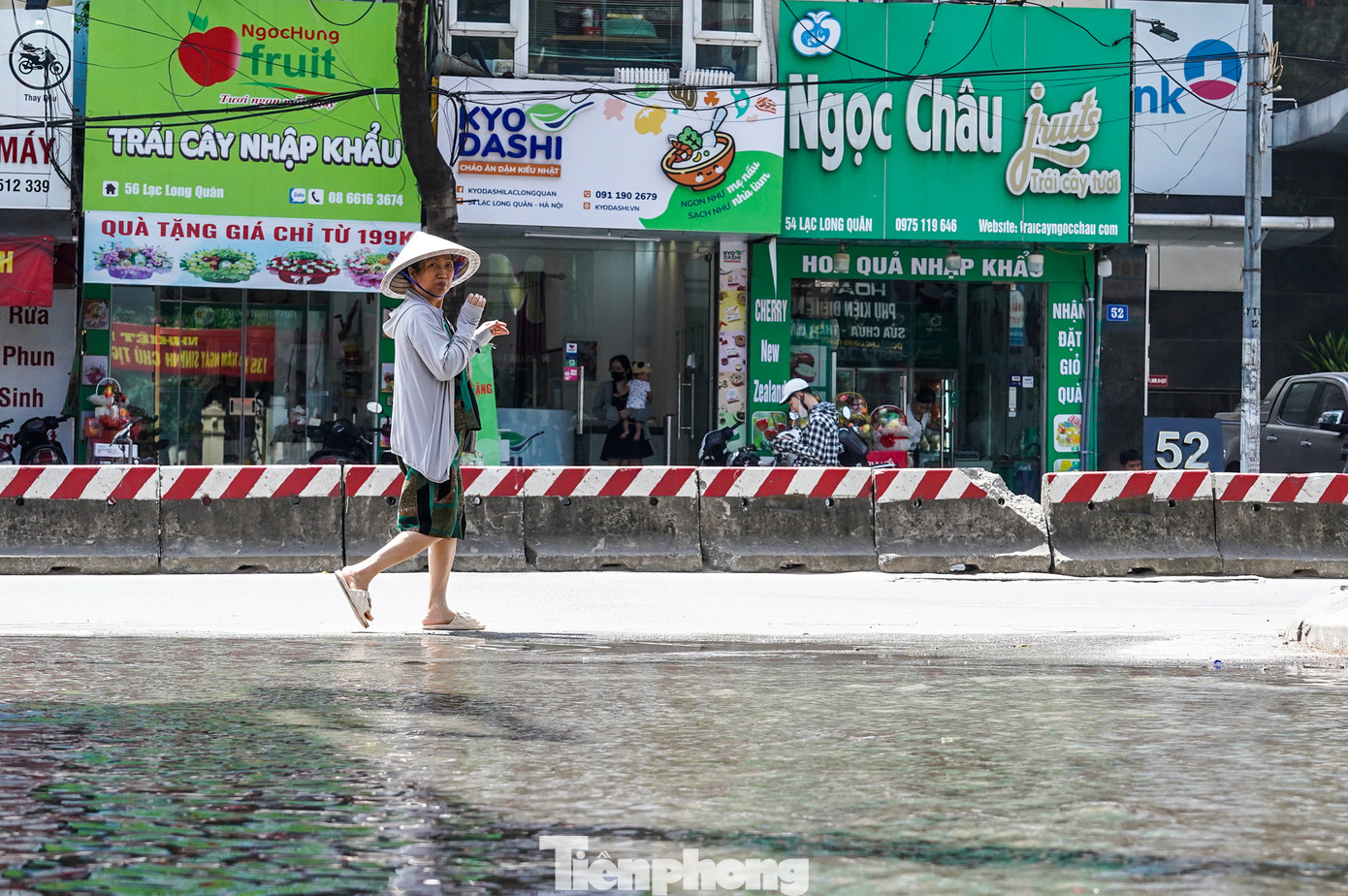 Người dân dùng vòi xịt nước ra mặt đường để hạ nhiệt, làm giảm hơi nóng bốc lên từ mặt nhựa giữa trưa hè.