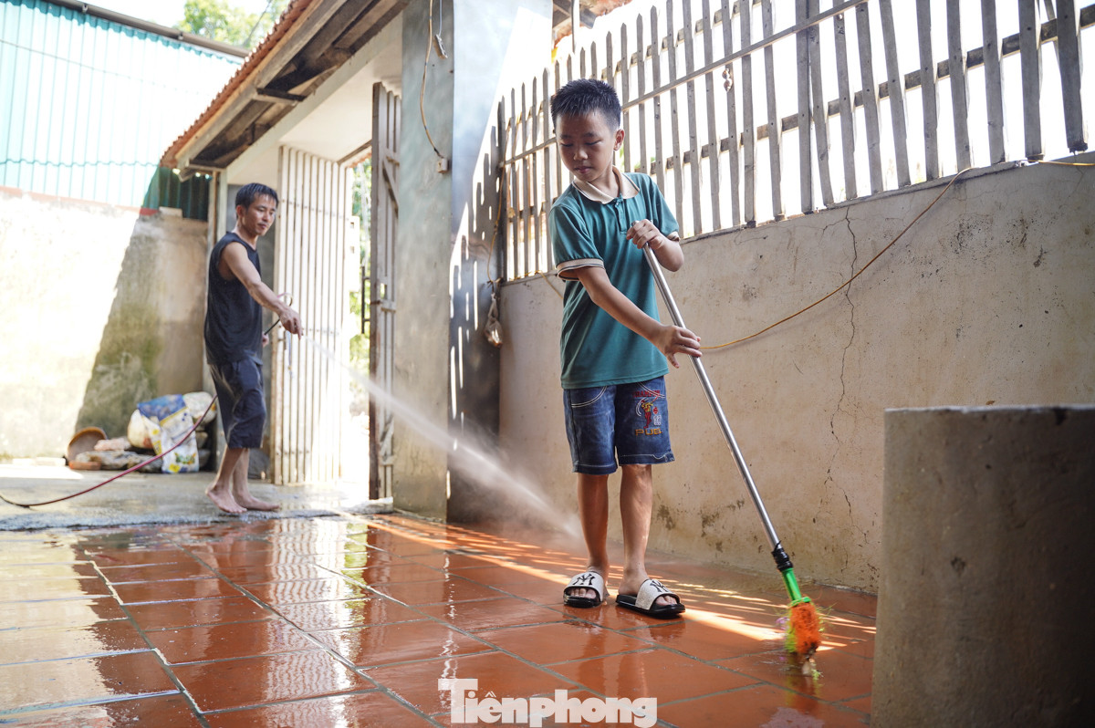 Hai bố con anh Nguyễn Trọng Tiến hối hả dọn dẹp nhà cửa sau khi nước lũ rút.
