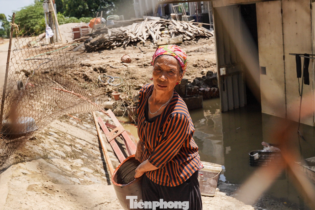 "Bùn đất bám đầy nhà, tôi tranh thủ về dọn dẹp bớt những thứ còn dùng được. Mong là mai kia nước rút hết để tôi còn về nhà mà ở", bà Nguyễn Thị Chuyển (78 tuổi) chia sẻ.