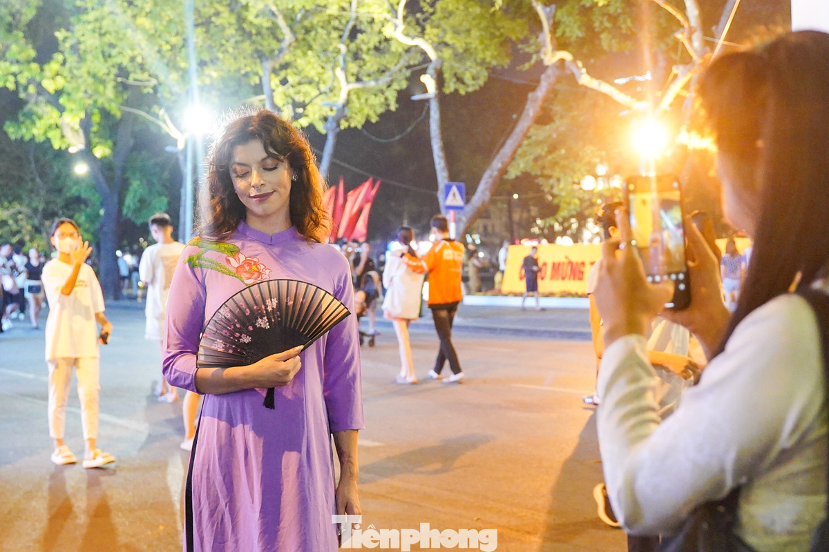 Du khách nước ngoài chụp ảnh với trang phục áo dài truyền thống Việt Nam.