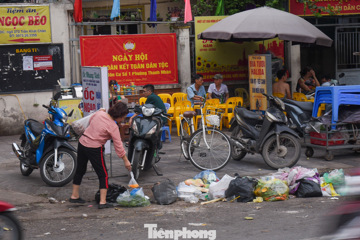 Một người phụ nữ mang rác sinh hoạt để công khai trước quán ăn trên đường Trần Khát Chân.