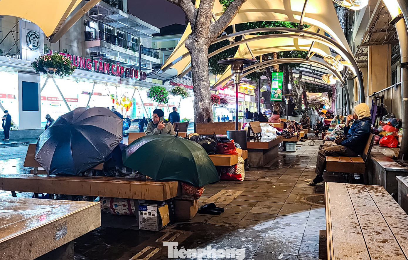 Thời tiết Hà Nội về đêm mưa liên tục, nhiều người phải sử dụng ô để che chắn xung quanh khu vực nghỉ ngơi nhằm tránh bị ướt.