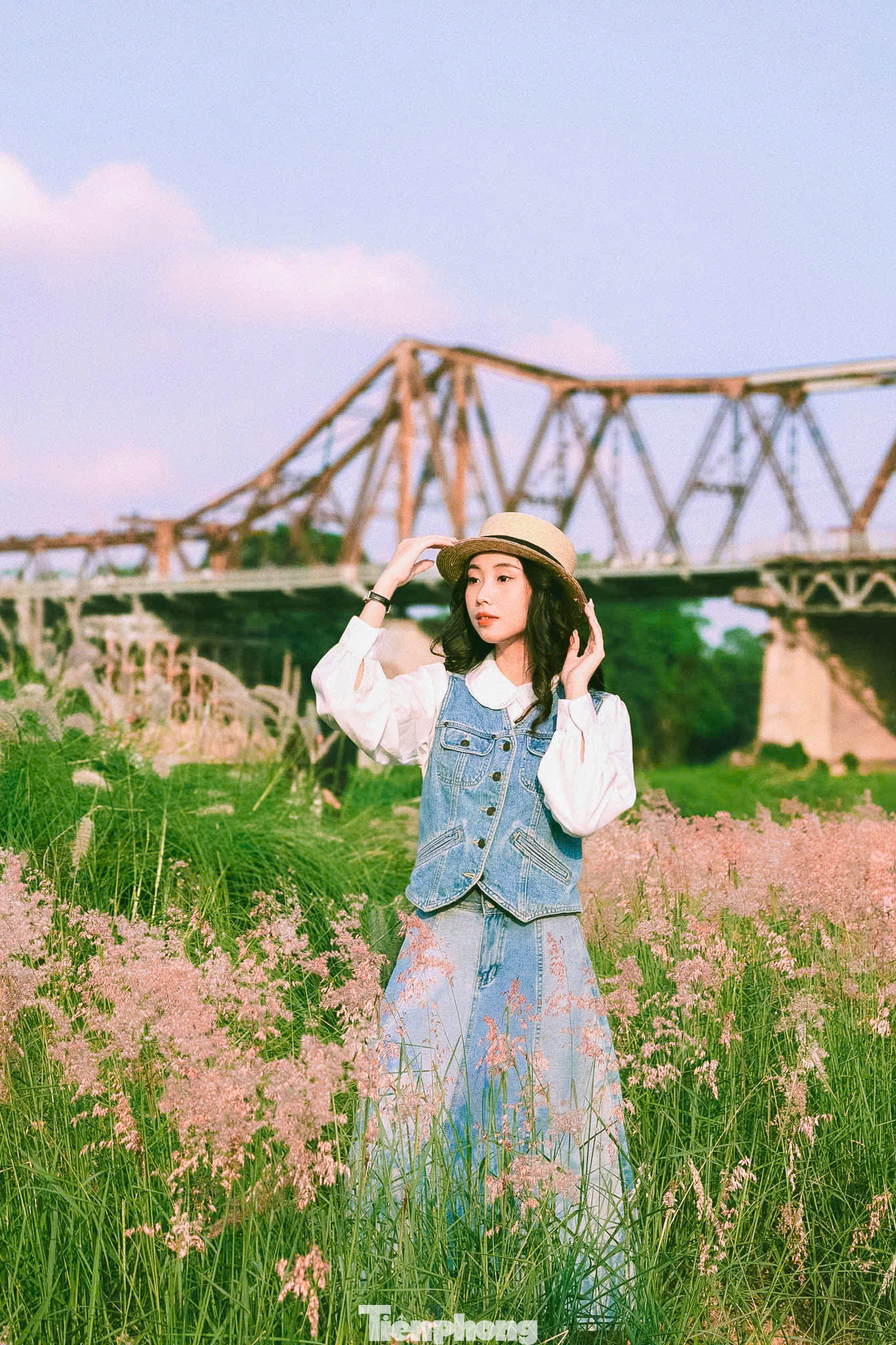 Các bạn trẻ hào hứng check-in, chụp ảnh bên bãi cỏ hồng rực rỡ, nổi bật trên nền cầu Long Biên cổ kính.