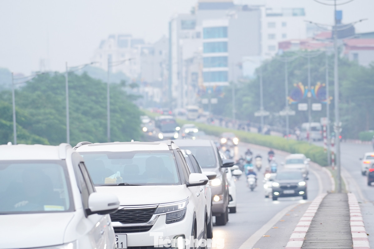 Gần 9 giờ sáng, hàng dài ô tô trên Vành đai 2 vẫn phải bật đèn vì bầu trời mù mịt do sương, khiến tầm nhìn giảm sút rõ rệt.