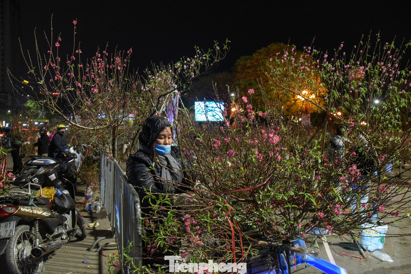 Chị Huyền Trang tranh thủ thu gom những cành đào chưa bán được để mang về nhà. "Năm nay không chờ 30 Tết nữa, tôi dọn hàng xong sáng mai về quê luôn, quê tận Nghệ An chờ hết ngày mai thì không kịp đón Giao Thừa", chị Trang tâm sự.