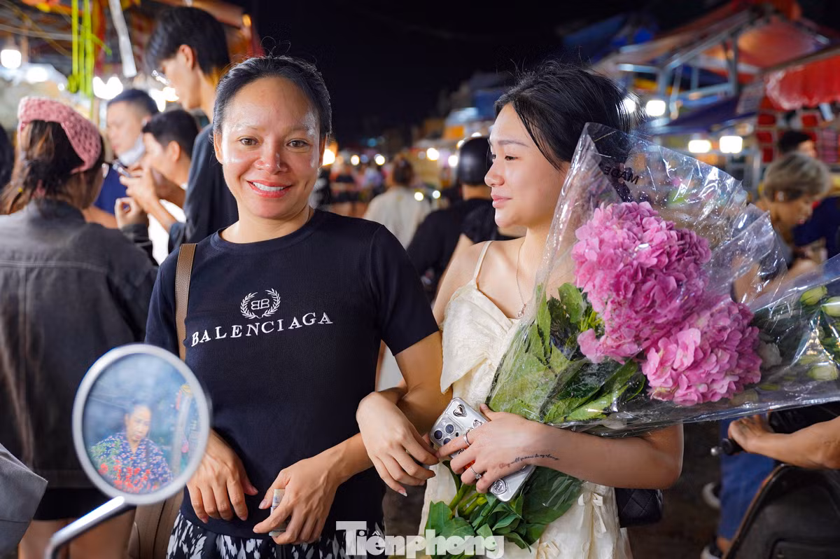 Hai mẹ con dẫn nhau đi tận hưởng không khí chợ đêm, chọn lựa một bó hoa tươi thắm nhất để mang về.