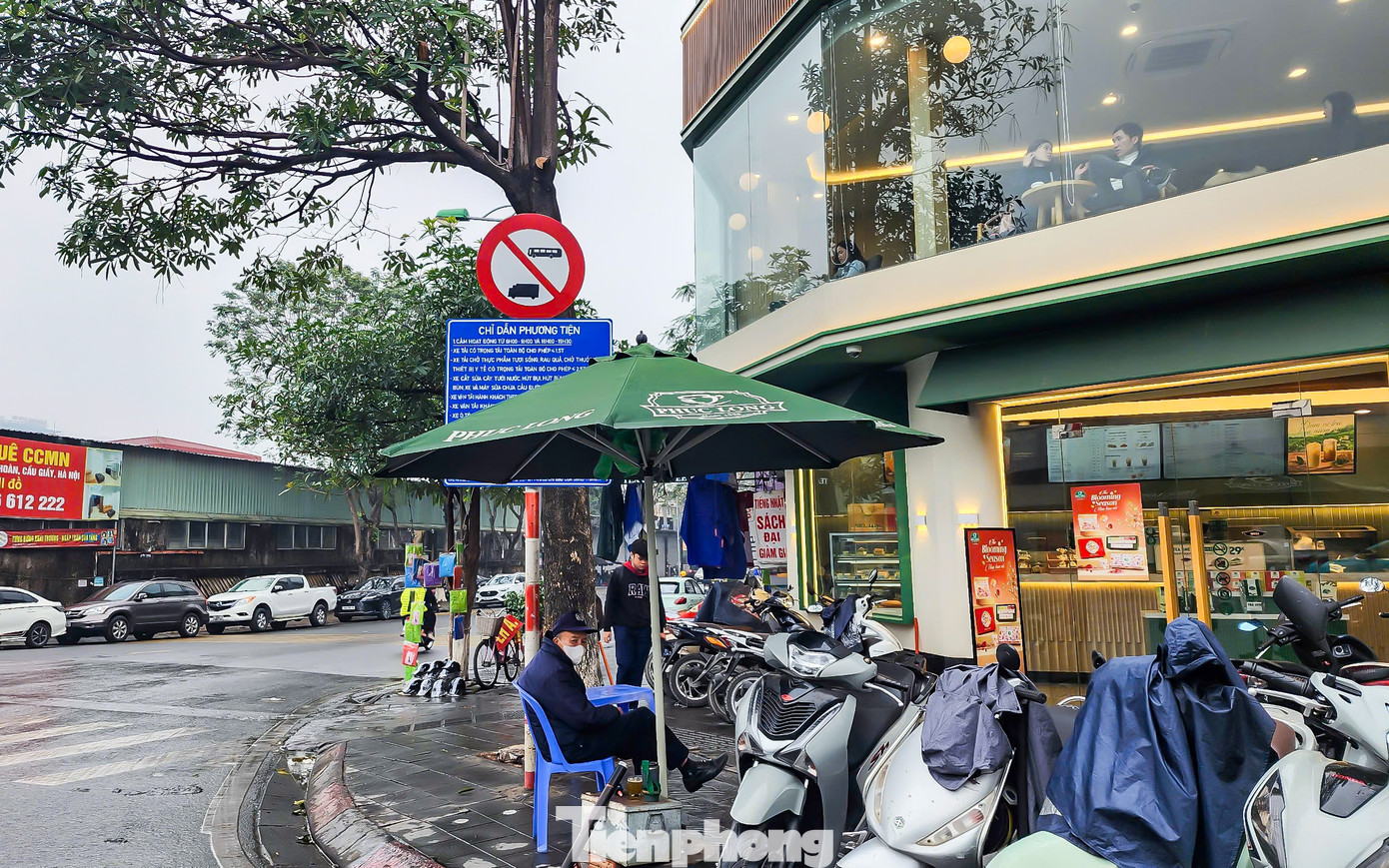 Tại đường Trần Quốc Hoàn (quận Cầu Giấy), một hộ kinh doanh đặt ô che khuất biển chỉ dẫn, gây cản trở tầm nhìn của người tham gia giao thông.