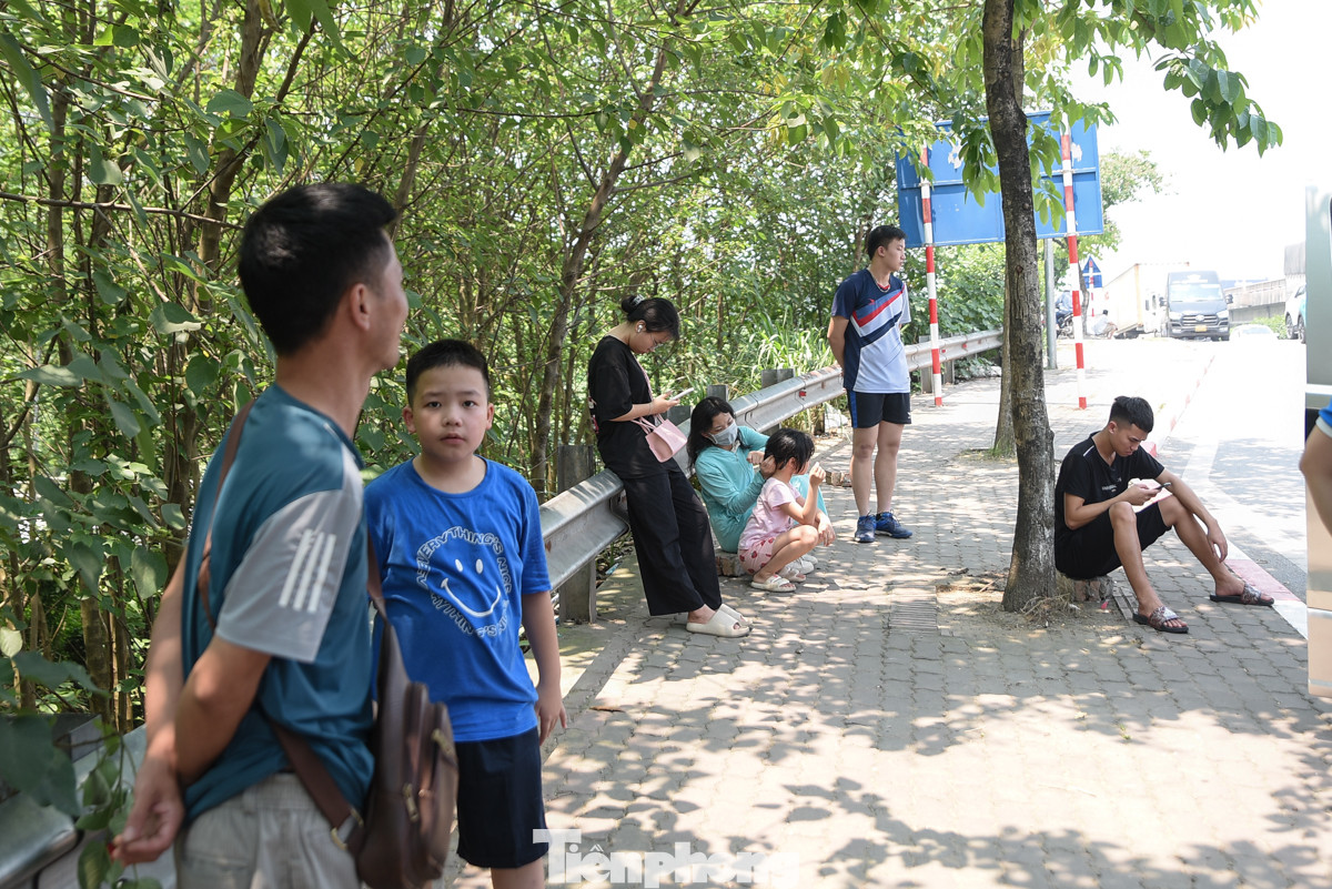 Người dân đứng chờ xe để về quê trên vỉa hè trong cái nắng hơn 38 độ của Thủ đô.