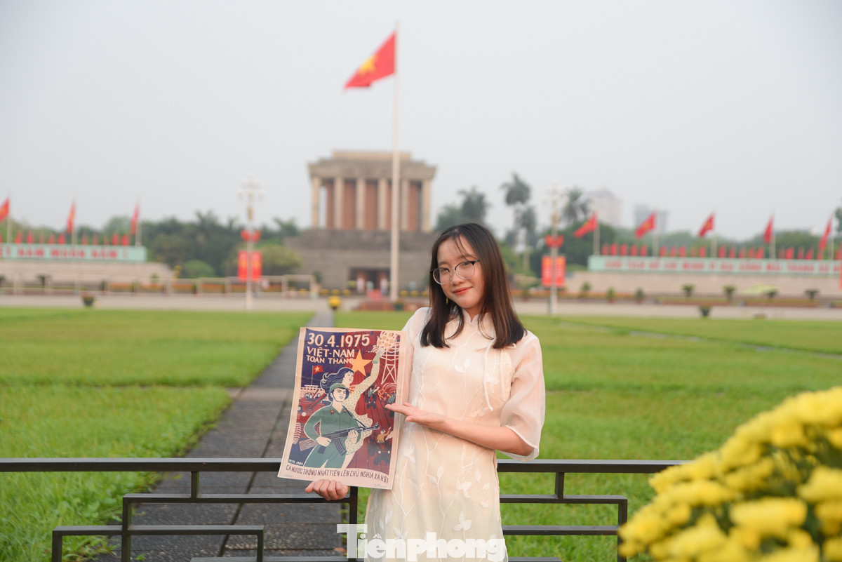 Một bạn trẻ cầm tấm poster Ngày Giải phóng miền Nam (30/4) chụp ảnh trước lăng Bác.