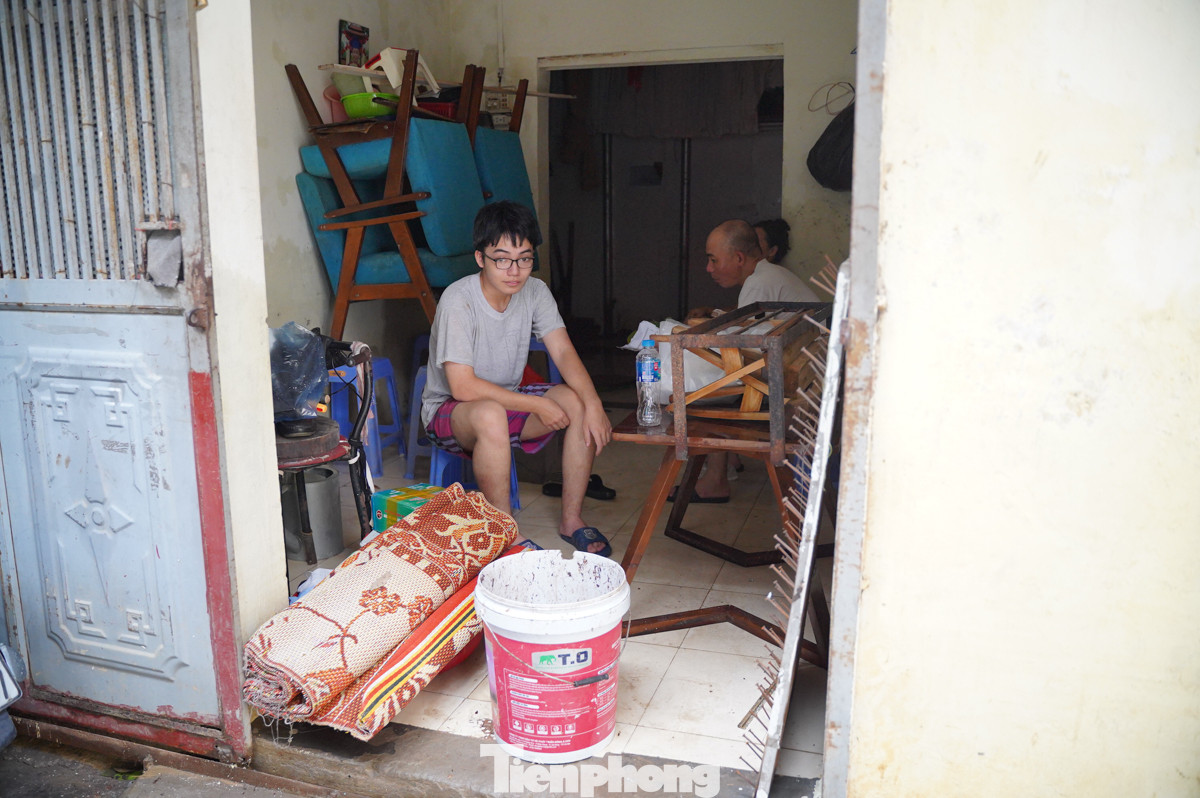 Một gia đình ngồi nghỉ mệt sau 8 tiếng liên tục dọn dẹp. "Nhà tôi chuyển đi nơi khác ở nên lúc về bùn đất rất nhiều, dọn mãi mới xong. May mắn là không thiệt hại gì cả", anh Nguyễn Anh Dũng (Chương Dương Độ) cho biết.