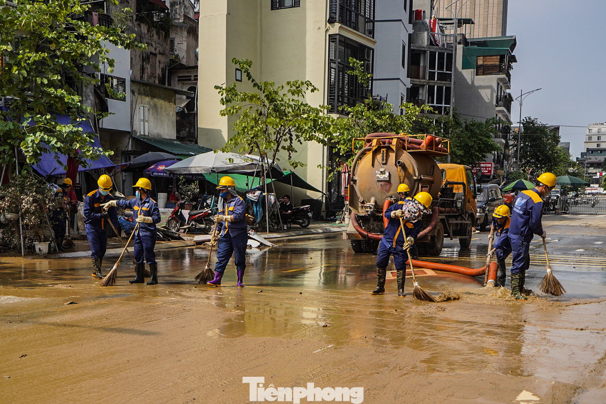 Các công nhân Công ty Thoát nước Hà Nội hỗ trợ người dân dọn dẹp đường phố, rửa trôi bùn đất.