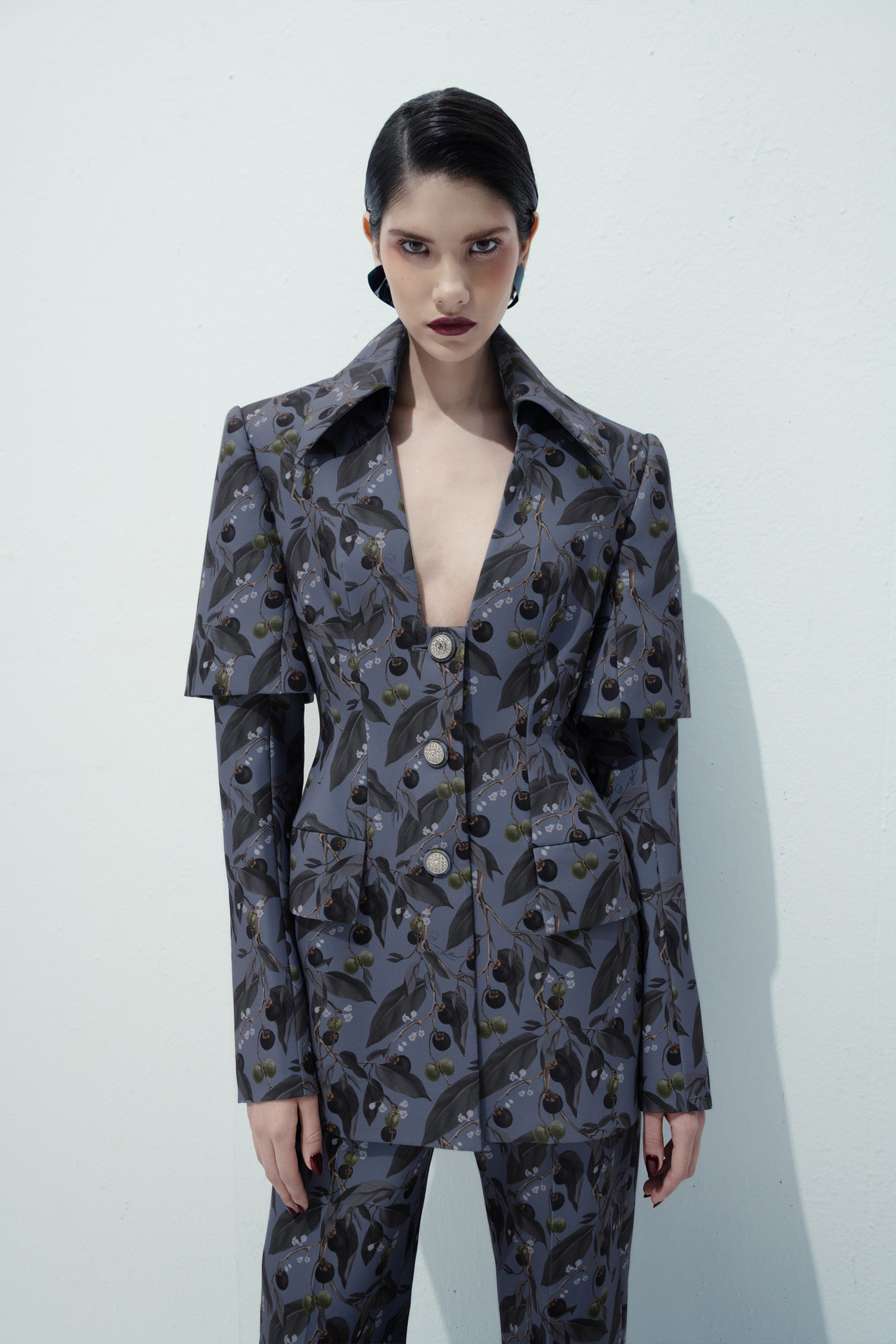 Thiết kế suit quyền lực với cấu trúc chiết eo, cổ khoét sâu tôn vinh sự nữ quyền.