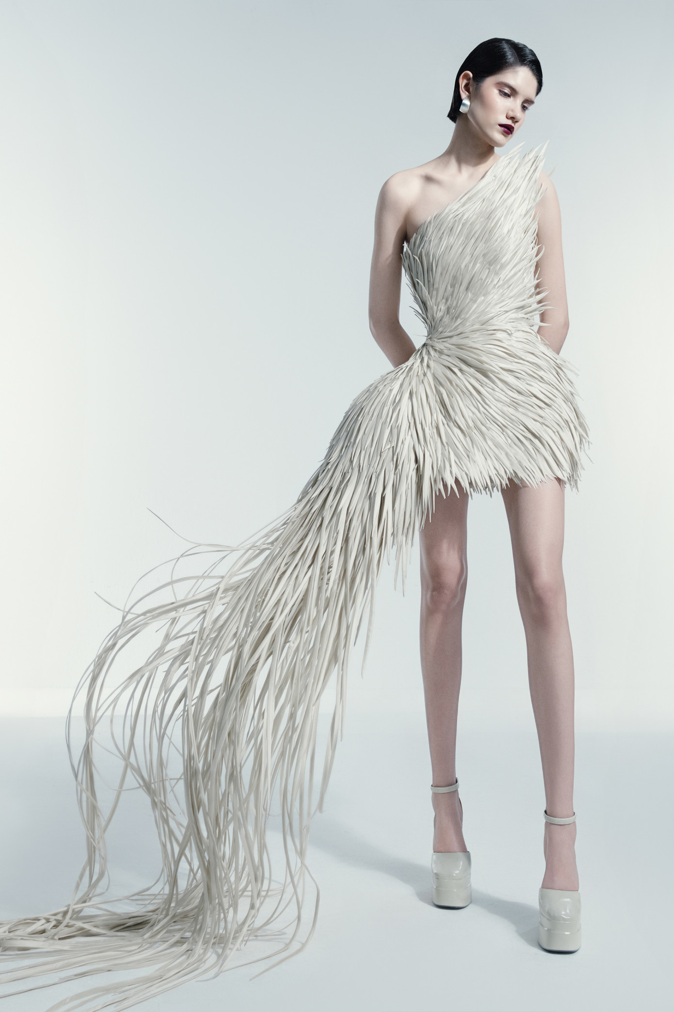 Thiết kế váy lệch vai độc đáo với chi tiết tua rua trải dài, tạo hiệu ứng chuyển động mềm mại.
