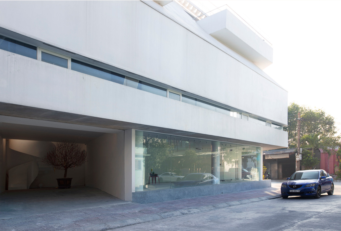 Với đặc điểm bối cảnh và diện tích đất tương đối nhỏ 136 m2, nhóm thiết kế đưa ra giải pháp để tầng 1 trống, với kính thông thoáng trải dài dọc hai bên mặt tiền, đảm bảo tính linh hoạt cho hoạt động kinh doanh.