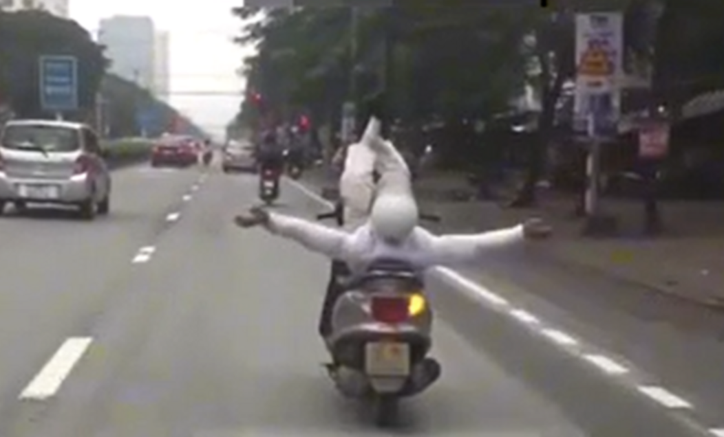 Hình ảnh người đàn ông dang hai tay hai chân khi điều khiển xe máy