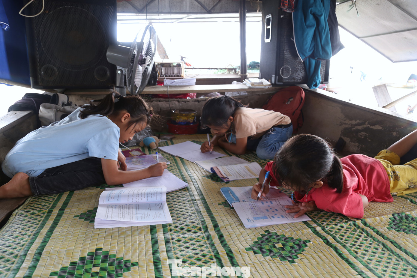 Không gian chật, không có bàn học. Những đứa trẻ làng chài phải nằm ra sàn thuyền để học bài.