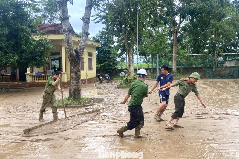 Lũ rút để lại lớp bùn đất nhão nhoẹt, cán bộ, chiến sĩ công an giúp dân dọn dẹp.