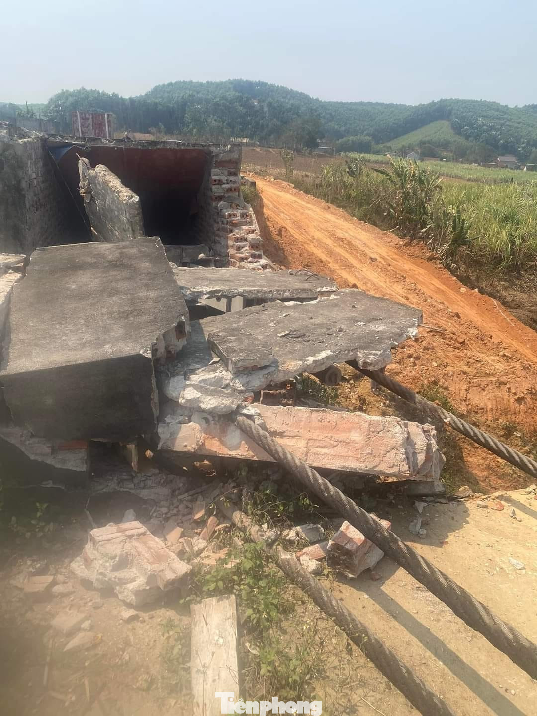 Phần mố cầu bị hư hỏng, nhiều trụ bêtông bị dây cáp kéo đổ nghiêng sát mép sông.