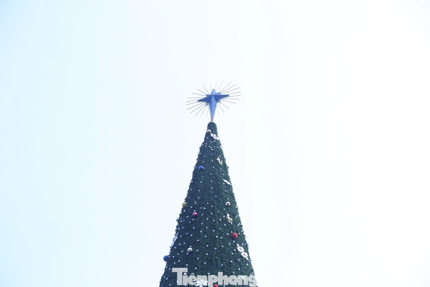 Phía trên cùng của cây thông là thánh giá có gắn đèn nháy Phía trên cùng của cây thông là thánh giá có gắn đèn nháy