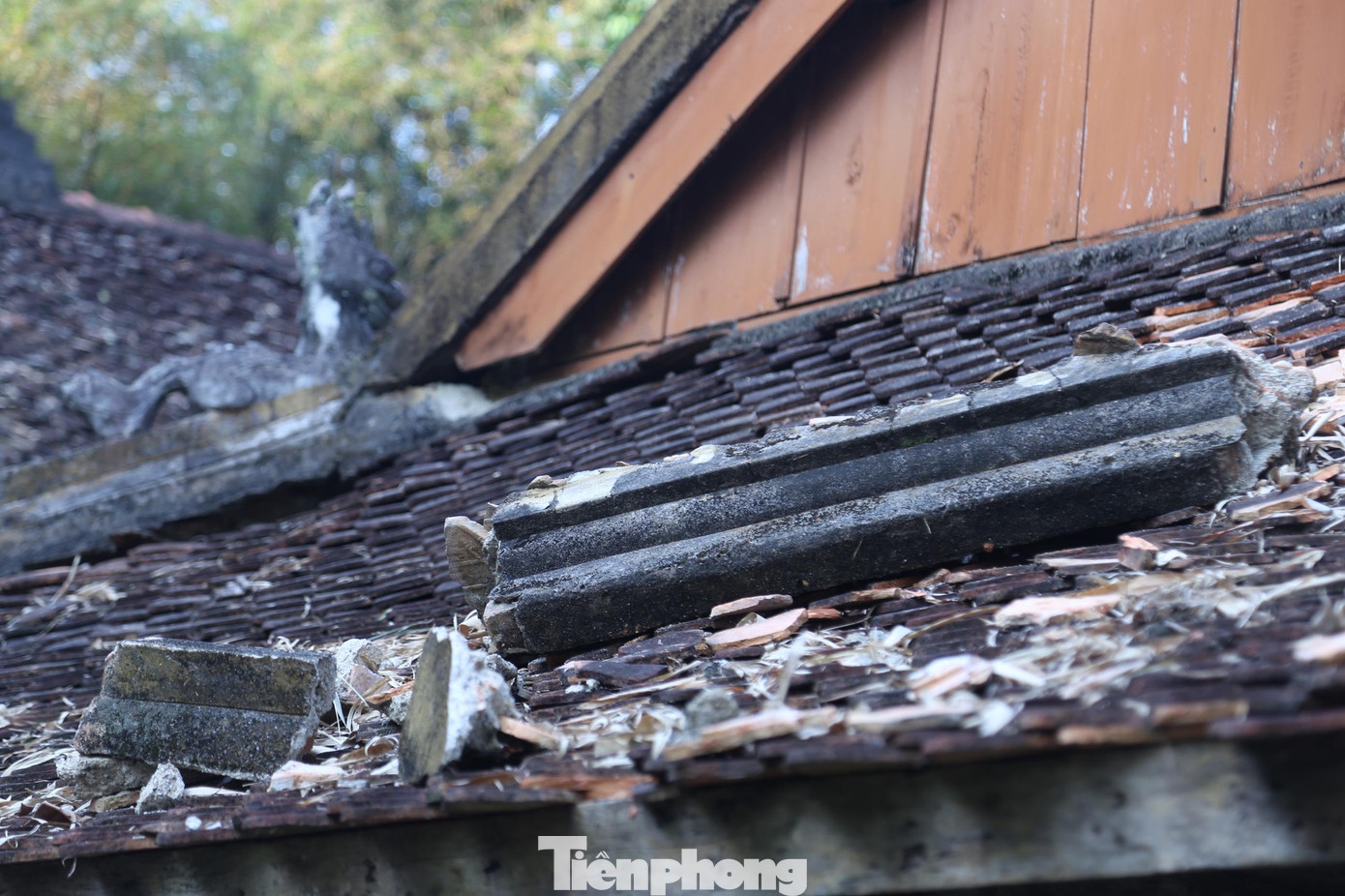 Một phần vôi vữa đường bờ mái ngói hạ điện đã rơi xuống đất nằm lộn xộn dưới chân tường, phần còn lại đang nằm trên mái hồi.