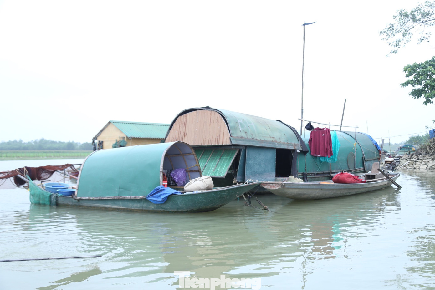 Kế bên "ngôi nhà" của ông Hoài là con thuyền nhỏ được lợp thêm mái tôn, che chắn tạm bởi mấy tấm ván gỗ nứt toác của người em trai Phạm Ngọc Hiệp (SN 1985). Con thuyền dập dềnh được anh cố định tạm bằng mấy tấm gỗ và sợi dây thừng buộc vào bờ sông. Kế bên "ngôi nhà" của ông Hoài là con thuyền nhỏ được lợp thêm mái tôn, che chắn tạm bởi mấy tấm ván gỗ nứt toác của người em trai Phạm Ngọc Hiệp (SN 1985). Con thuyền dập dềnh được anh cố định tạm bằng mấy tấm gỗ và sợi dây thừng buộc vào bờ sông.