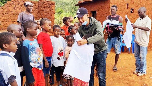 Quang Linh (ở giữa) trao đồng phục, cặp sách hỗ trợ trẻ em ở làng Sanzala (huyện Bailundo, tỉnh Huambo, Angola).