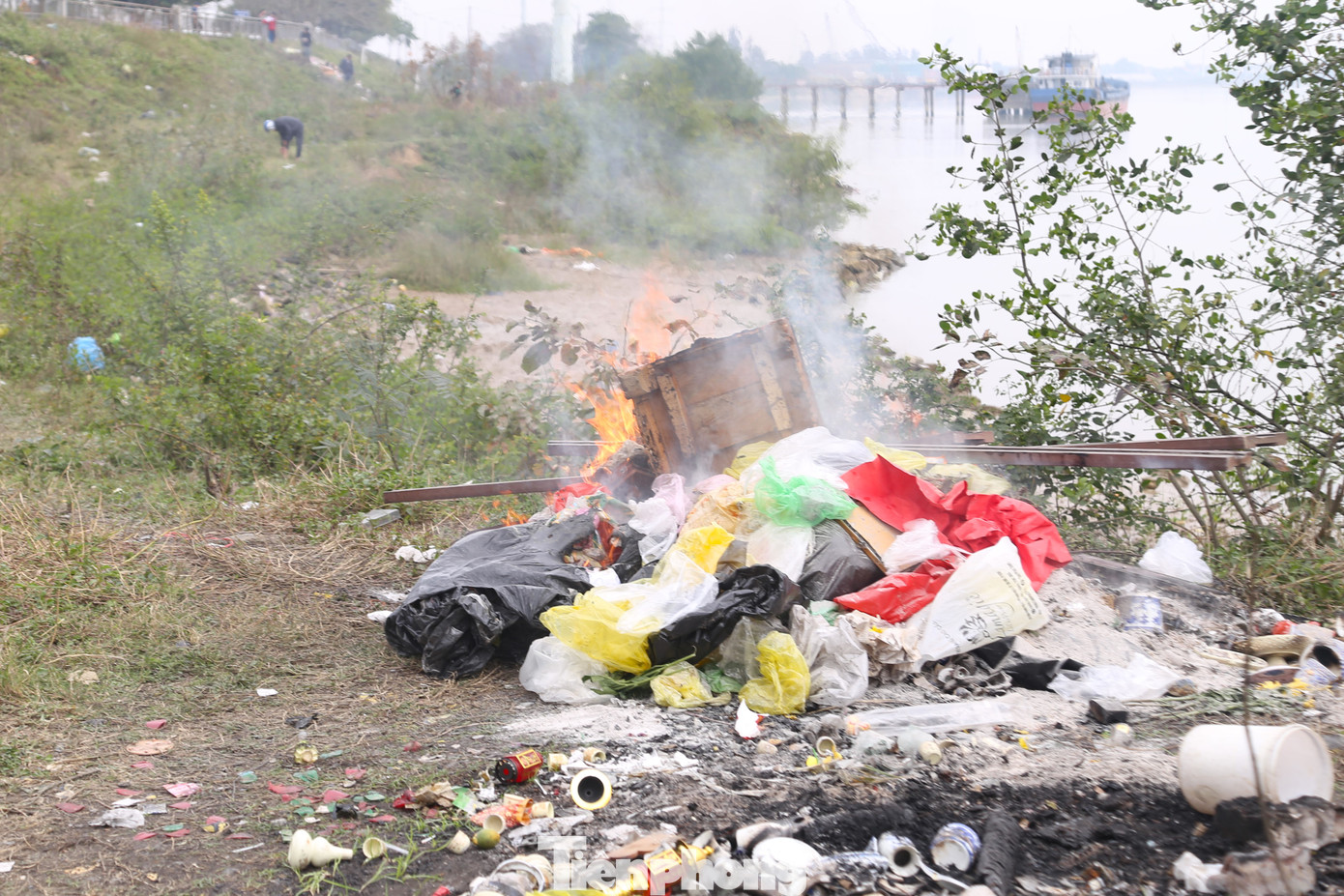Một số người khác mang túi ni lông lên bờ để đốt, gây ô nhiễm môi trường. Trên bờ, ngập rác thải, đồ thờ cúng do người dân để lại.