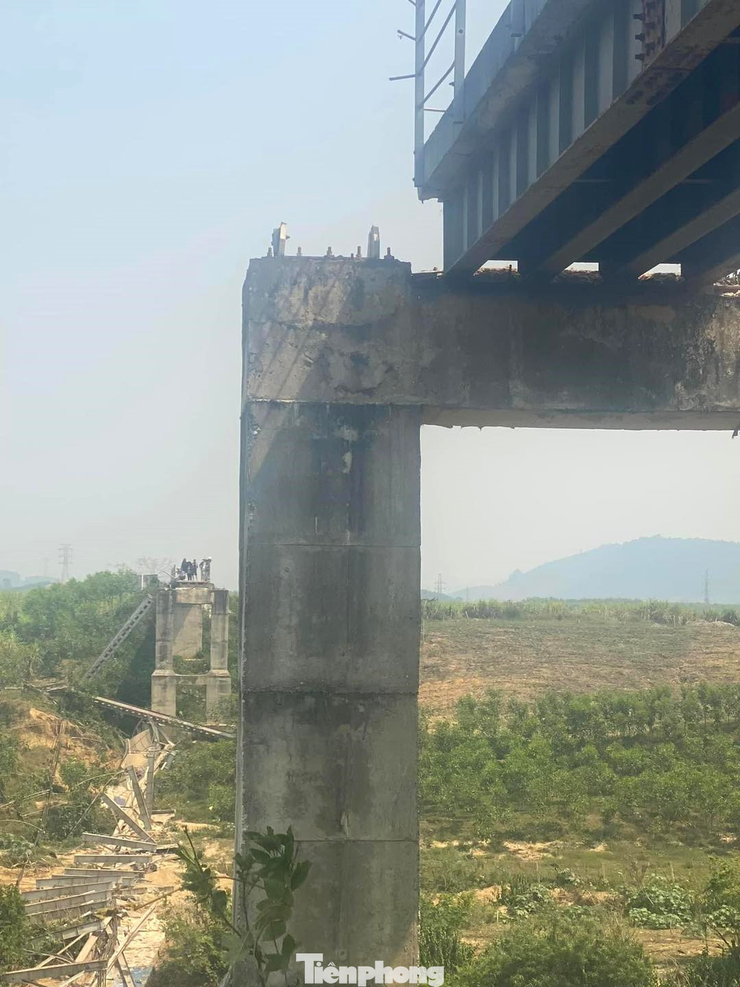 Phần mố cầu bị hư hỏng, nhiều trụ bêtông bị dây cáp kéo đổ nghiêng sát mép sông.