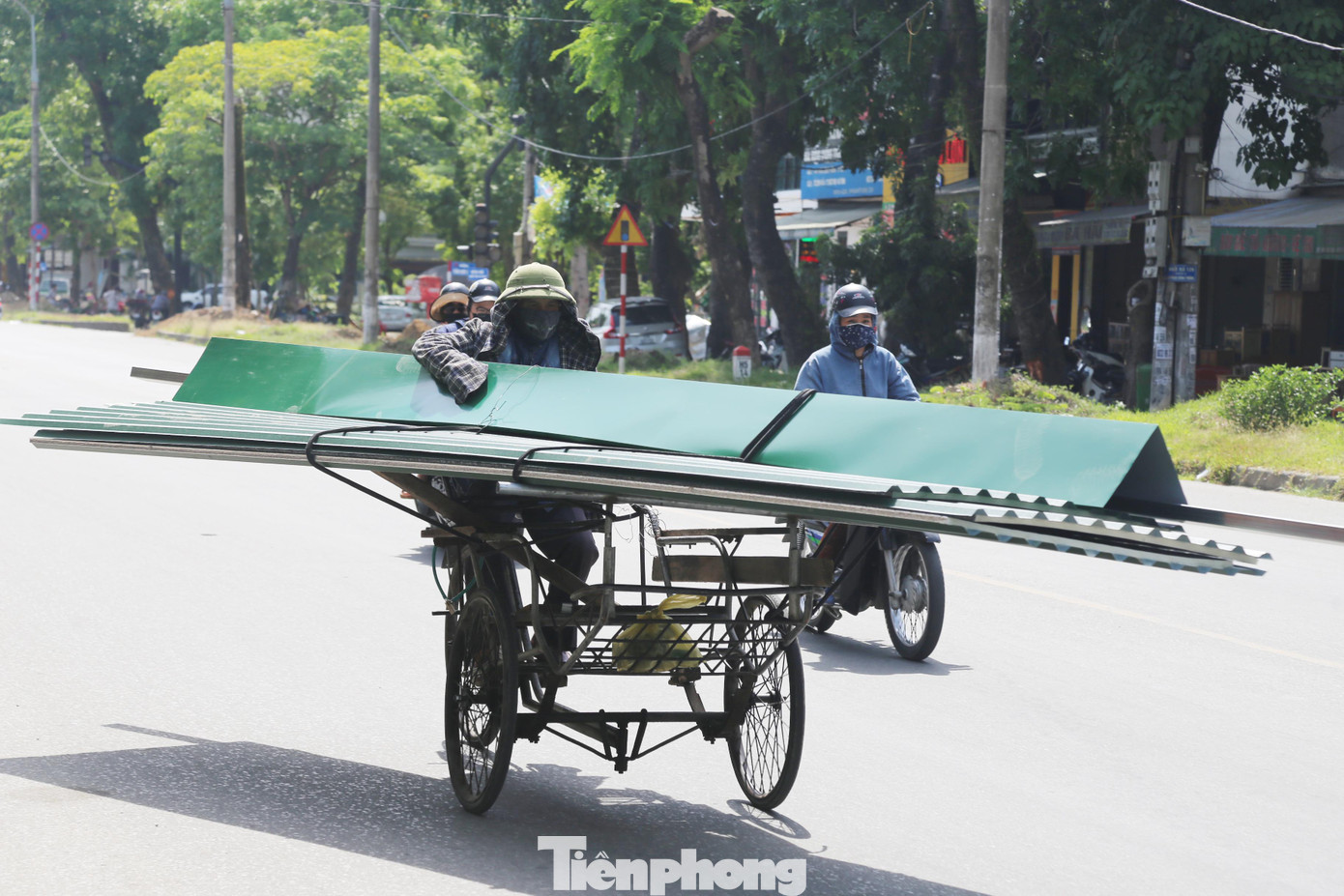 Người đàn ông hành nghề đạp xích lô chở hàng 'bở hơi tai' khi vận chuyển xe hàng cồng kềnh giữa nắng gắt.