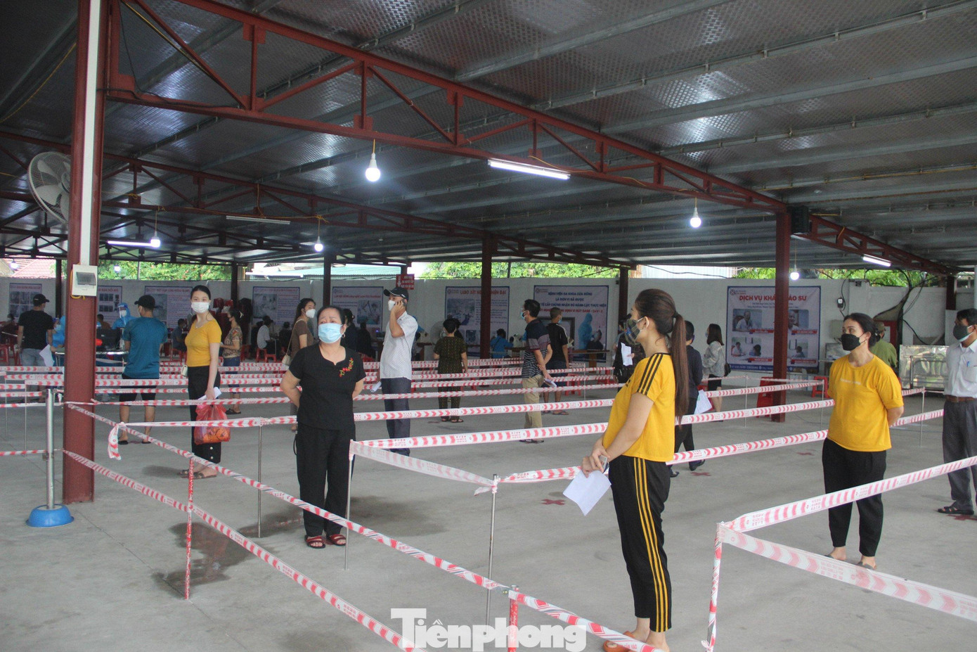 Các tiểu thương giữ khoảng cách trước khi tiêm vắcxin phòng COVID-19