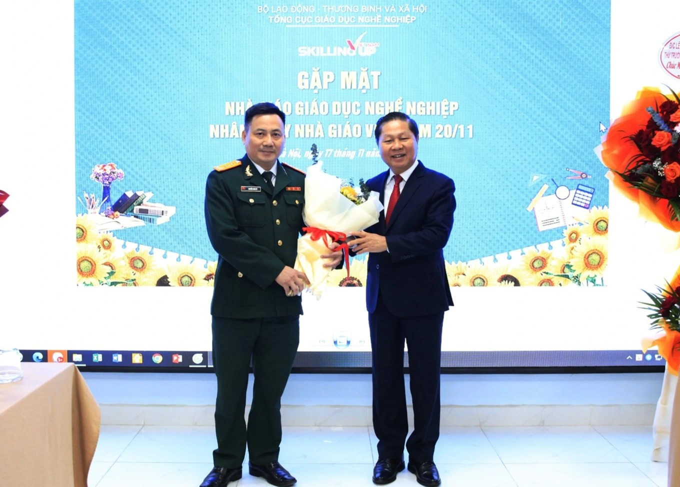 Thầy Nguyễn Minh Tú đón nhận hoa chúc mừng của ông Lê Tấn Dũng, Thứ trưởng Bộ Lao động - Thương binh và Xã hội.