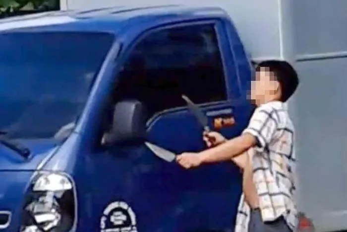Thanh niên hai tay hai dao chém vỡ gương xe tải. Ảnh cắt từ clip