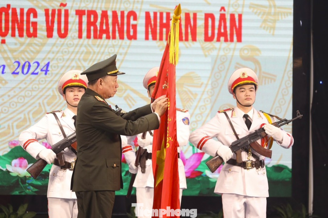 Đại tướng Tô Lâm - Ủy viên Bộ Chính trị, Bí thư Đảng ủy Công an T.Ư, Bộ trưởng Bộ Công an gắn Huy hiệu Anh hùng Lực lượng vũ trang Nhân dân lên lá cờ truyền thống của ngành