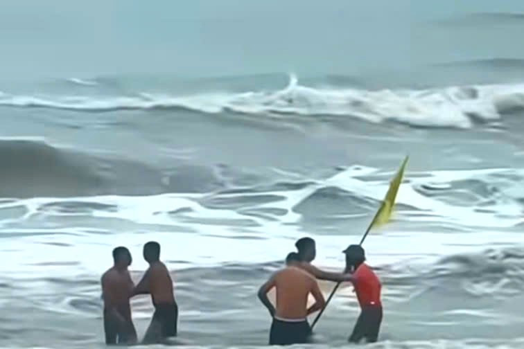 Hình ảnh nam nhân viên cầm cờ lao xuống biển ngăn du khách tắm lúc sóng to gió lớn