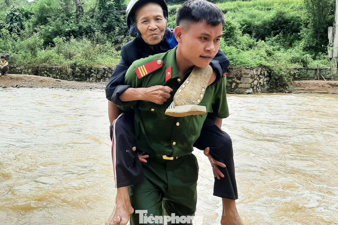 Chiến sĩ công an hỗ trợ người dân di chuyển qua dòng nước chảy xiết.