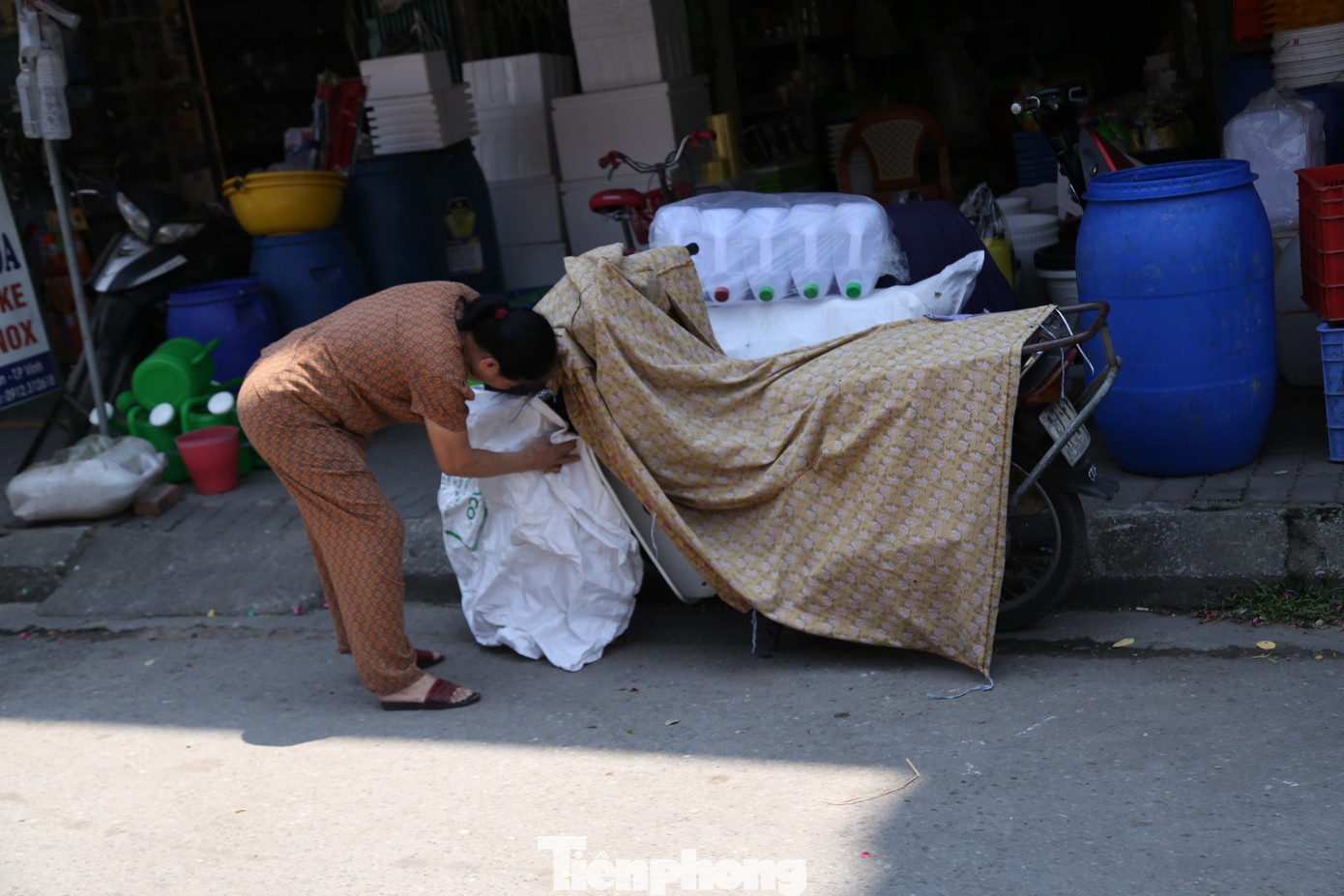 Người phụ nữ lấy bao bì để chống nắng cho xe máy ở khu vực chợ Vinh.