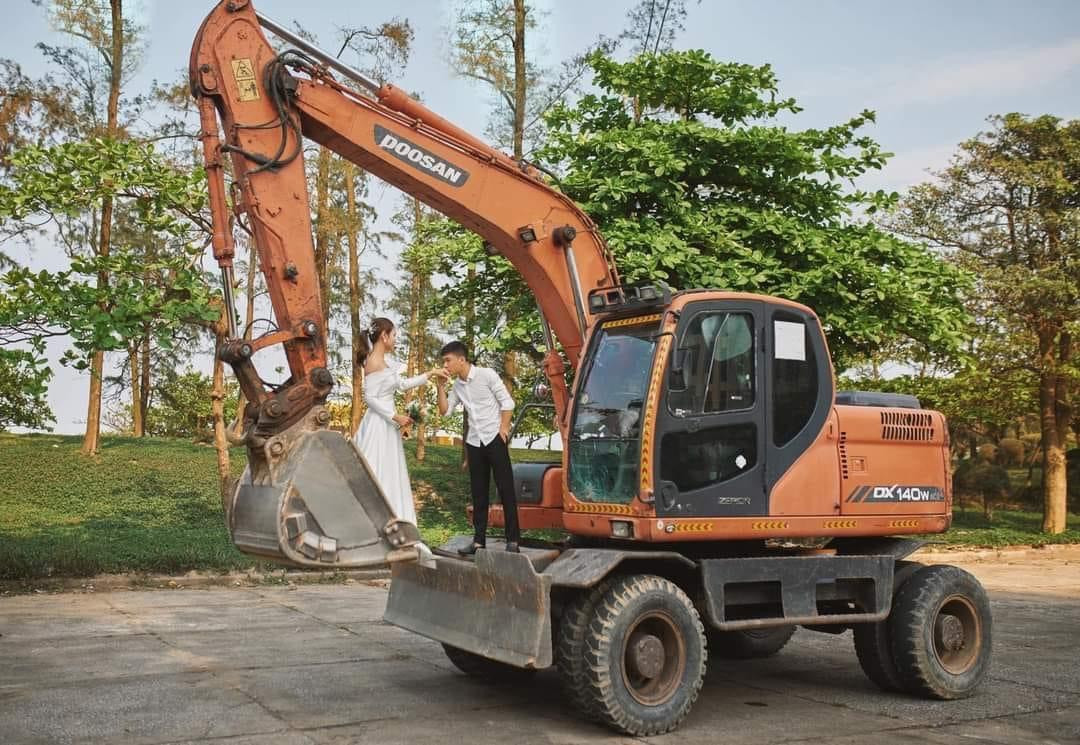Chú rể và cô dâu chụp ảnh cưới với máy xúc