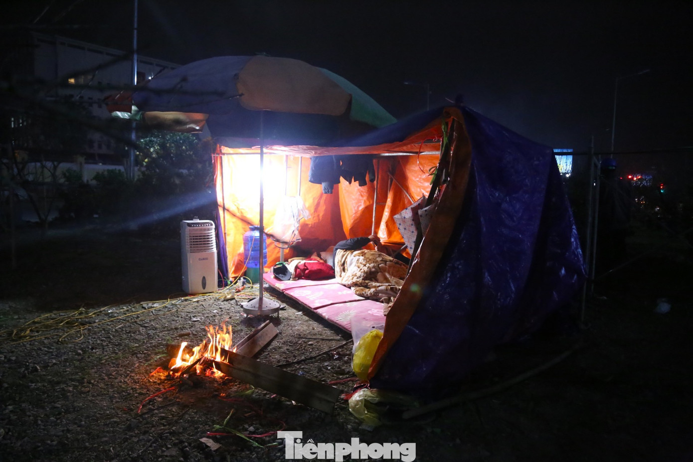 Trước những túp lều được dựng tạm bợ để canh đào, quất ngày Tết, người dân đốt lửa tìm hơi ấm.