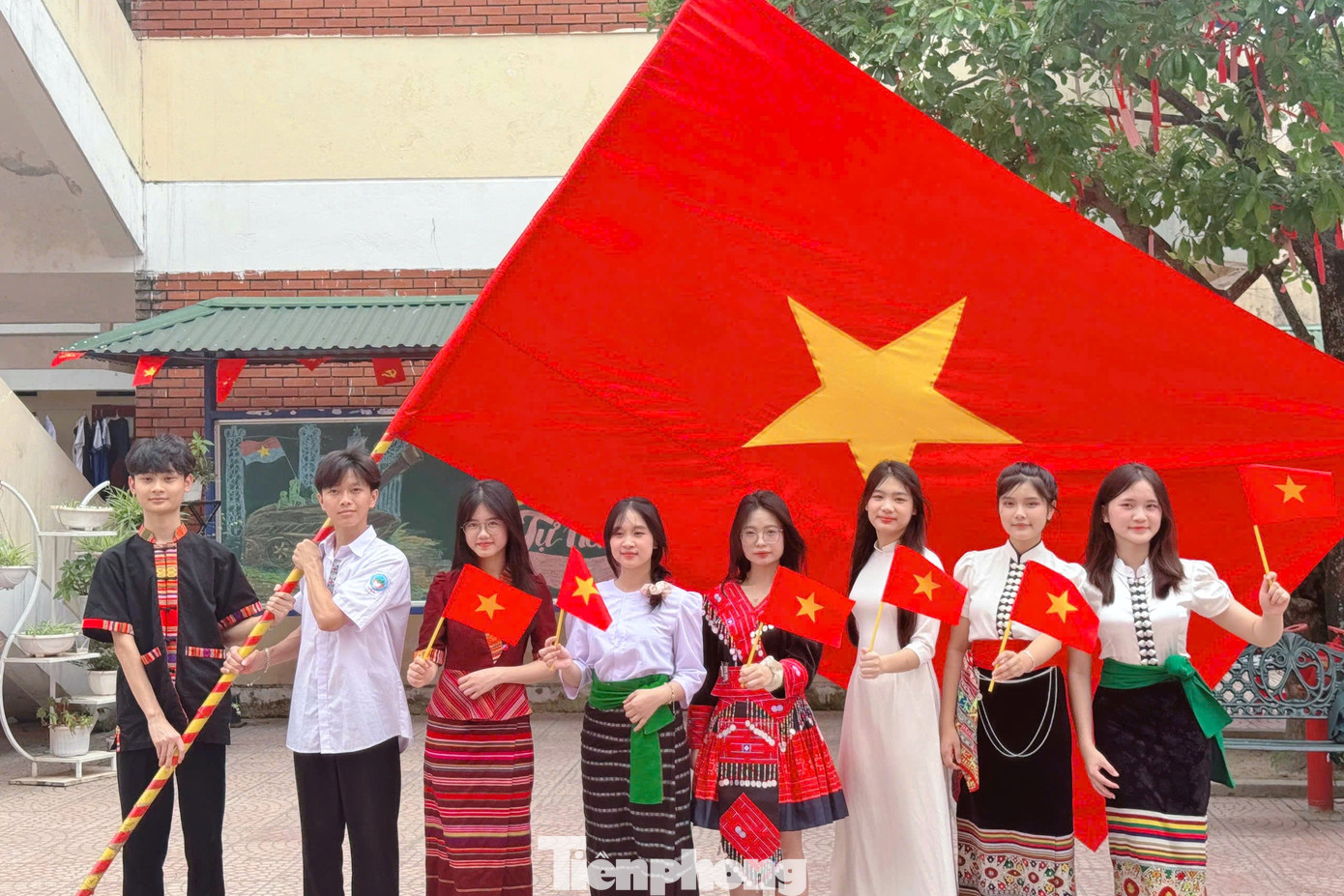 Học sinh Trường THPT Dân tộc nội trú Nghệ An trong trang phục dân tộc bên lá cờ Tổ quốc.
