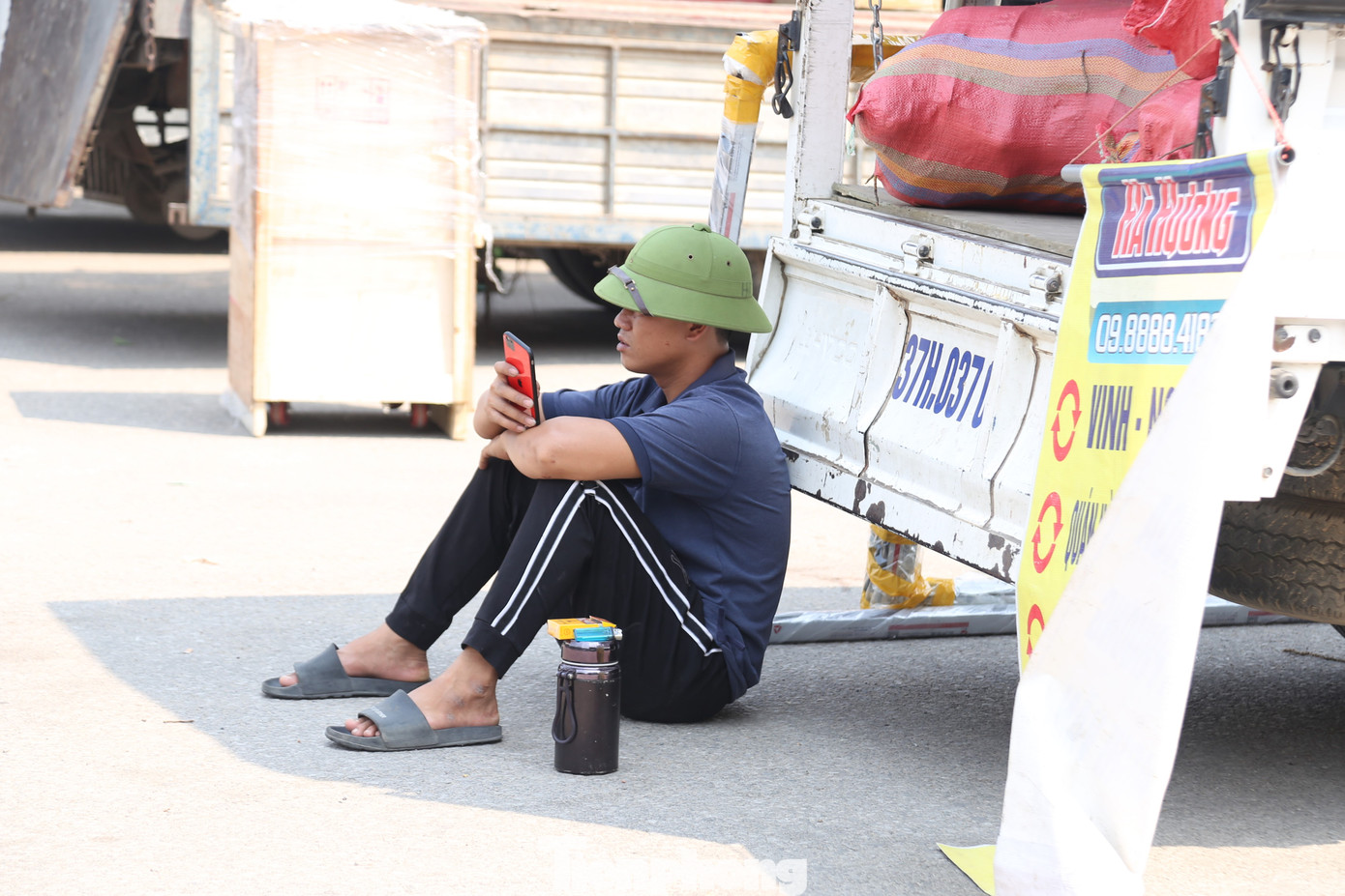Tranh thủ khi chưa có hàng để bốc, người cửu vạn nương theo bóng râm của thùng xe ngồi nghỉ.